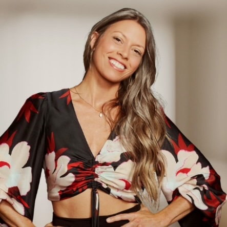 Joy Rigel smiling in a warm-toned floral blouse