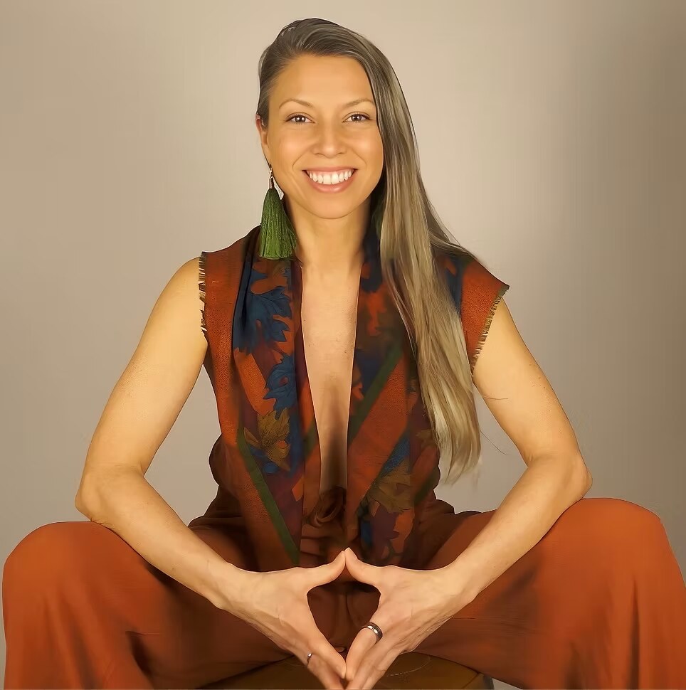 Joy Rigel, intimacy and relationship coach, seated in warm earth-toned attire